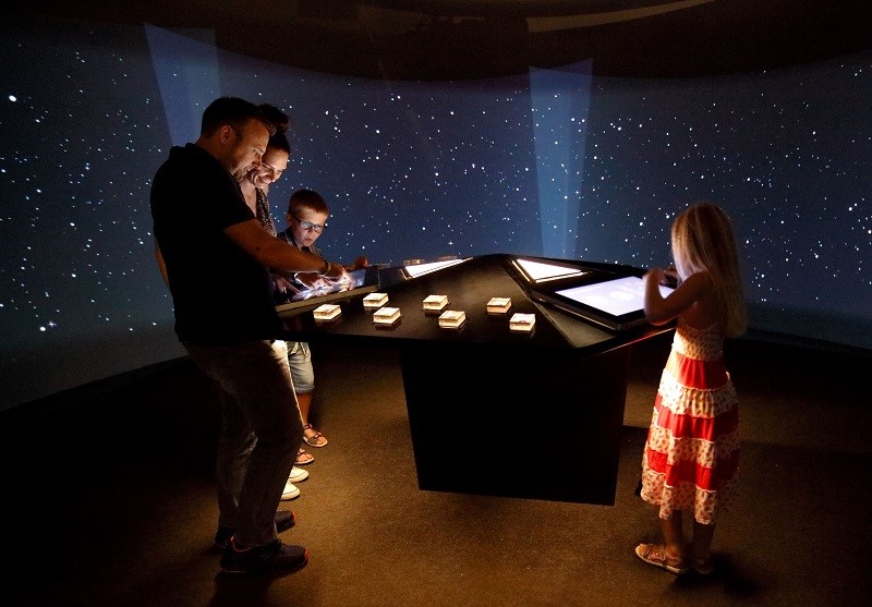 Družina v Centru Noordung v sobi VESOLJE 360 raziskuje vesolje
